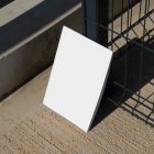 Front view, of a white outdoor magazine mockup resists on a metal net fence in black color.