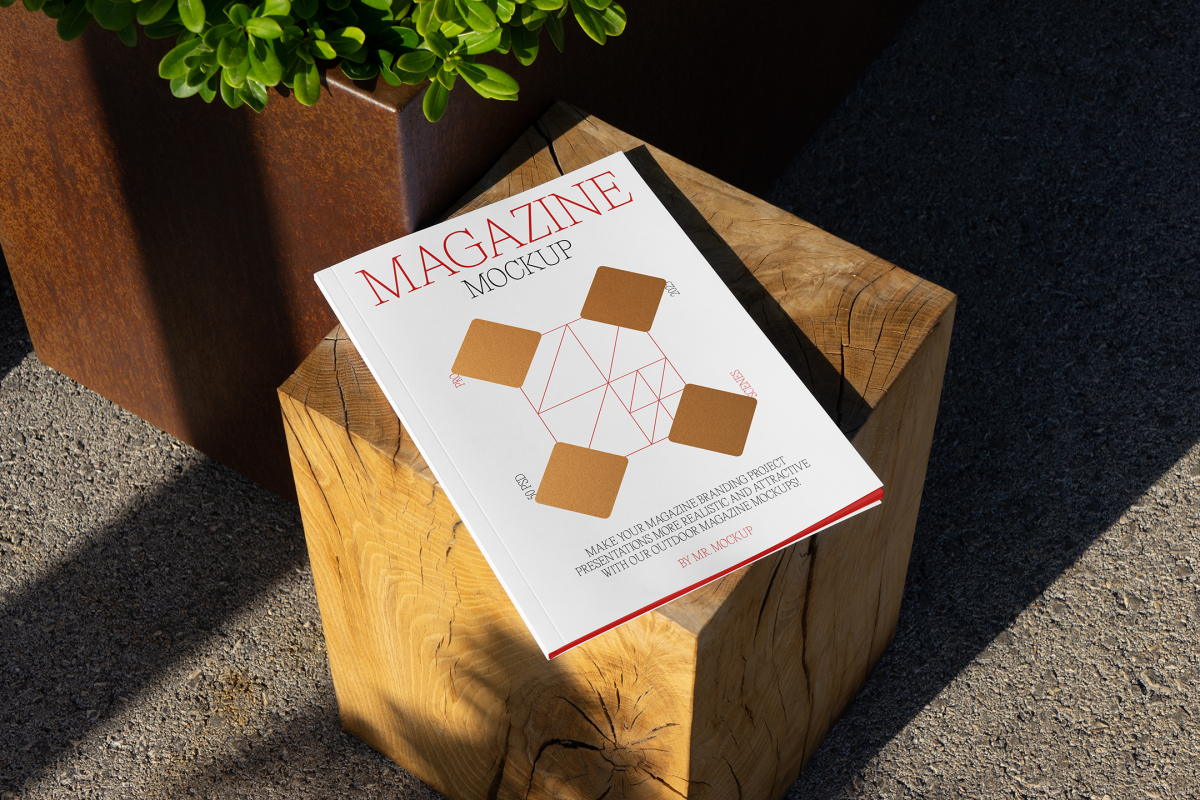 View from above, of outdoor magazine mockups with simple minimalist design in black and red color, serif typography, and diamond foil pattern laying on wooden square.