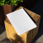 View from above, of a white outdoor magazine mockup laying on a wooden square.