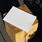 View from above, of a white outdoor magazine mockup laying on a wooden square.