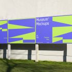 Front view, Three Rectangle Banner Mockup with white, purple, and neon green geometric designs and metal construction standing in front of the beige building wall. Scene from our Museum Mockups product.