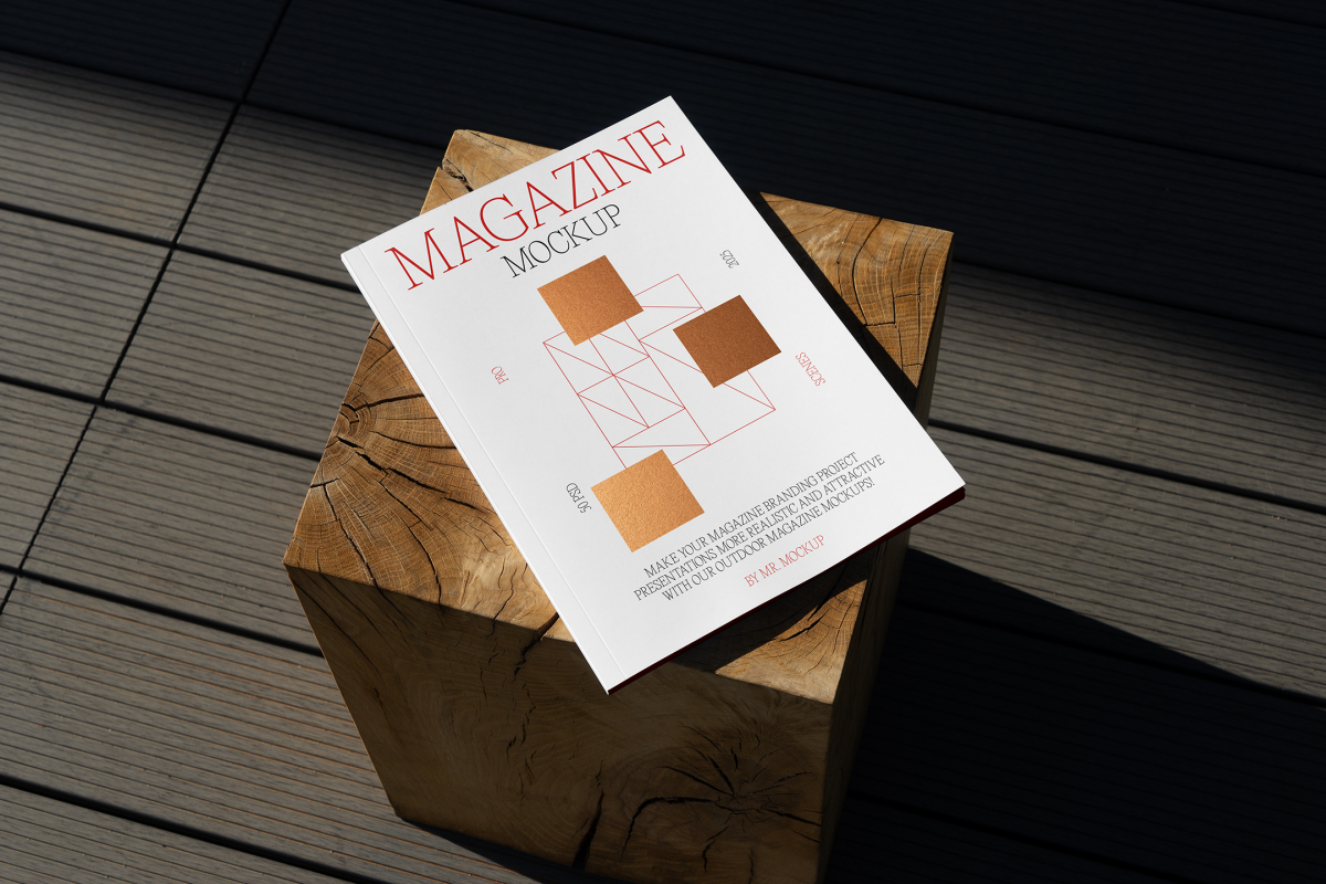View from above, of outdoor magazine mockups with simple minimalist design in black and red color, serif typography, and square foil pattern laying on a wooden square.