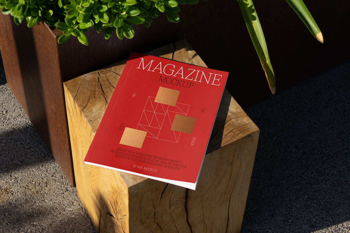 View from above, of outdoor magazine mockups with simple minimalist design in black and red color, serif typography, and square foil pattern laying on a wooden square.
