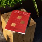 View from above, of outdoor magazine mockups with simple minimalist design in black and red color, serif typography, and square foil pattern laying on a wooden square.