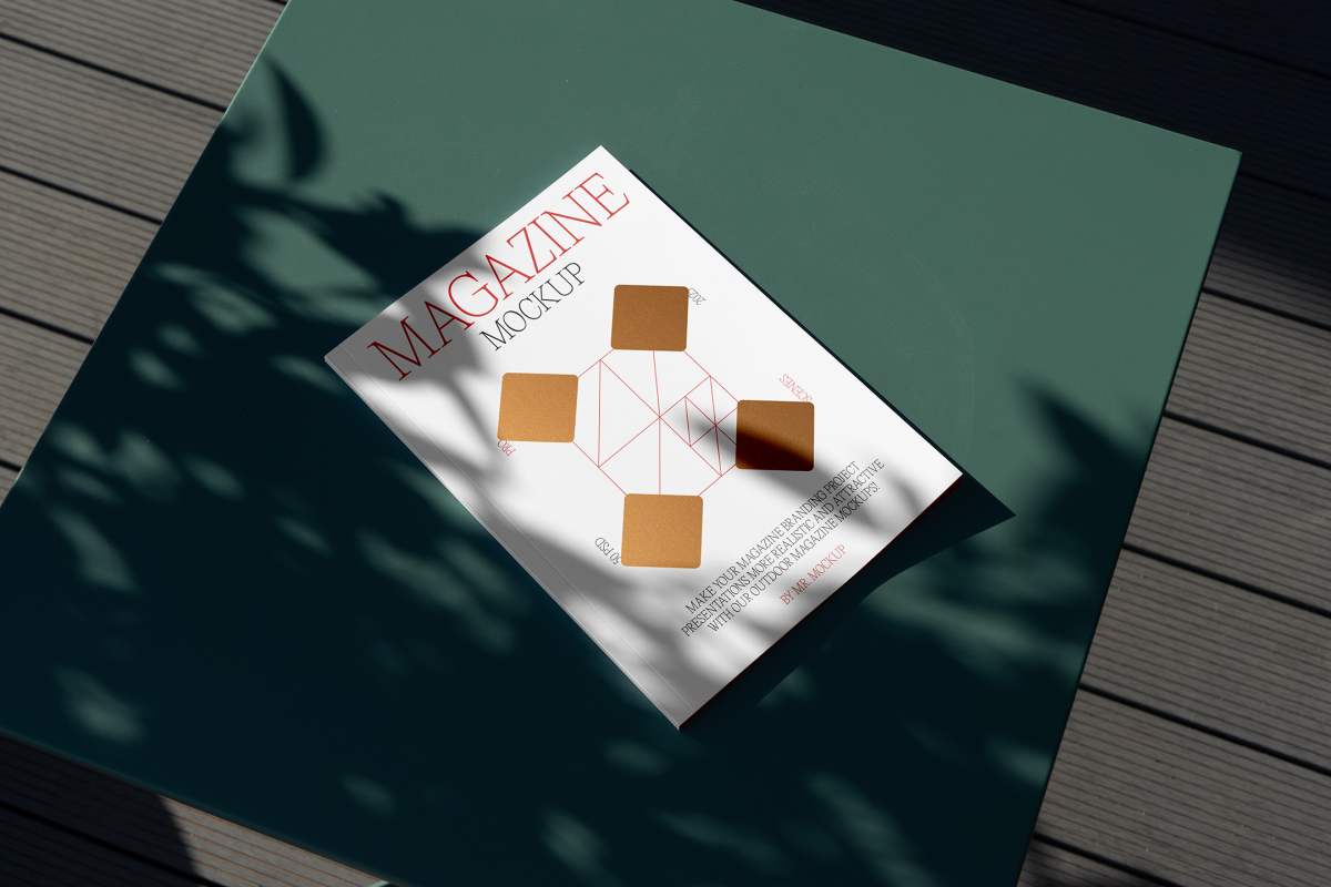 View from above, of outdoor magazine mockups with simple minimalist design in black and red color, serif typography, and diamond foil pattern laying on a green table.
