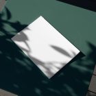 View from above, of a white outdoor magazine mockup laying on a green table.