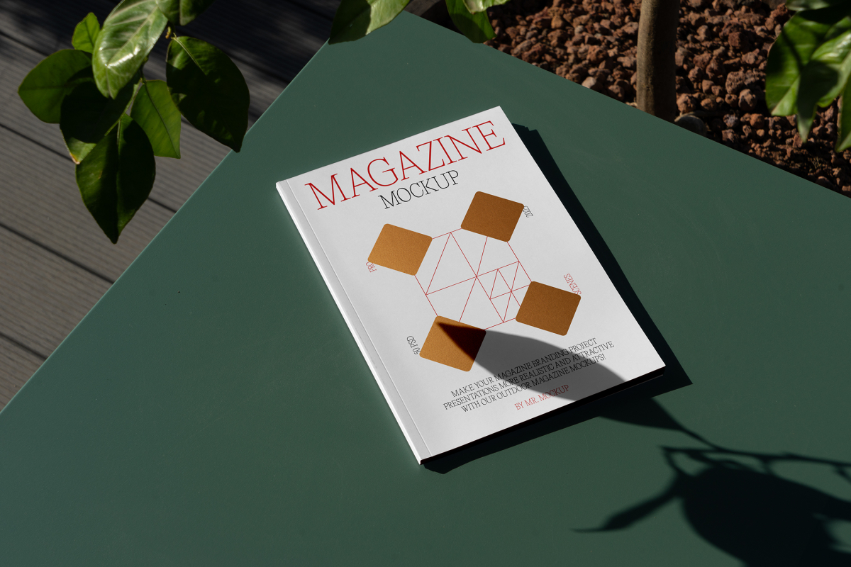 View from above, of outdoor magazine mockups with simple minimalist design in black and red color, serif typography, and diamond foil pattern laying on a green table.