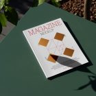 View from above, of outdoor magazine mockups with simple minimalist design in black and red color, serif typography, and diamond foil pattern laying on a green table.