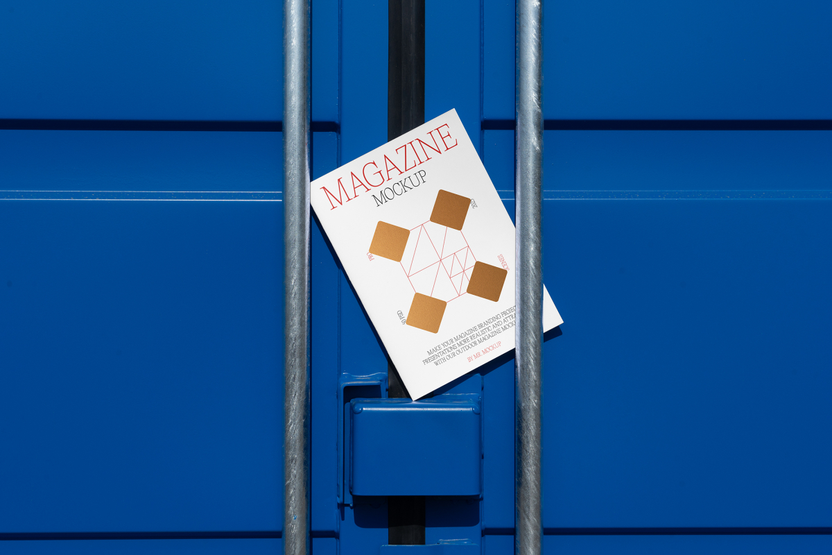 Front view, of outdoor magazine mockups with simple minimalist designs in black and red colors, serif typography, and diamond foil patterns lies between a blue container and a silver metal tube.