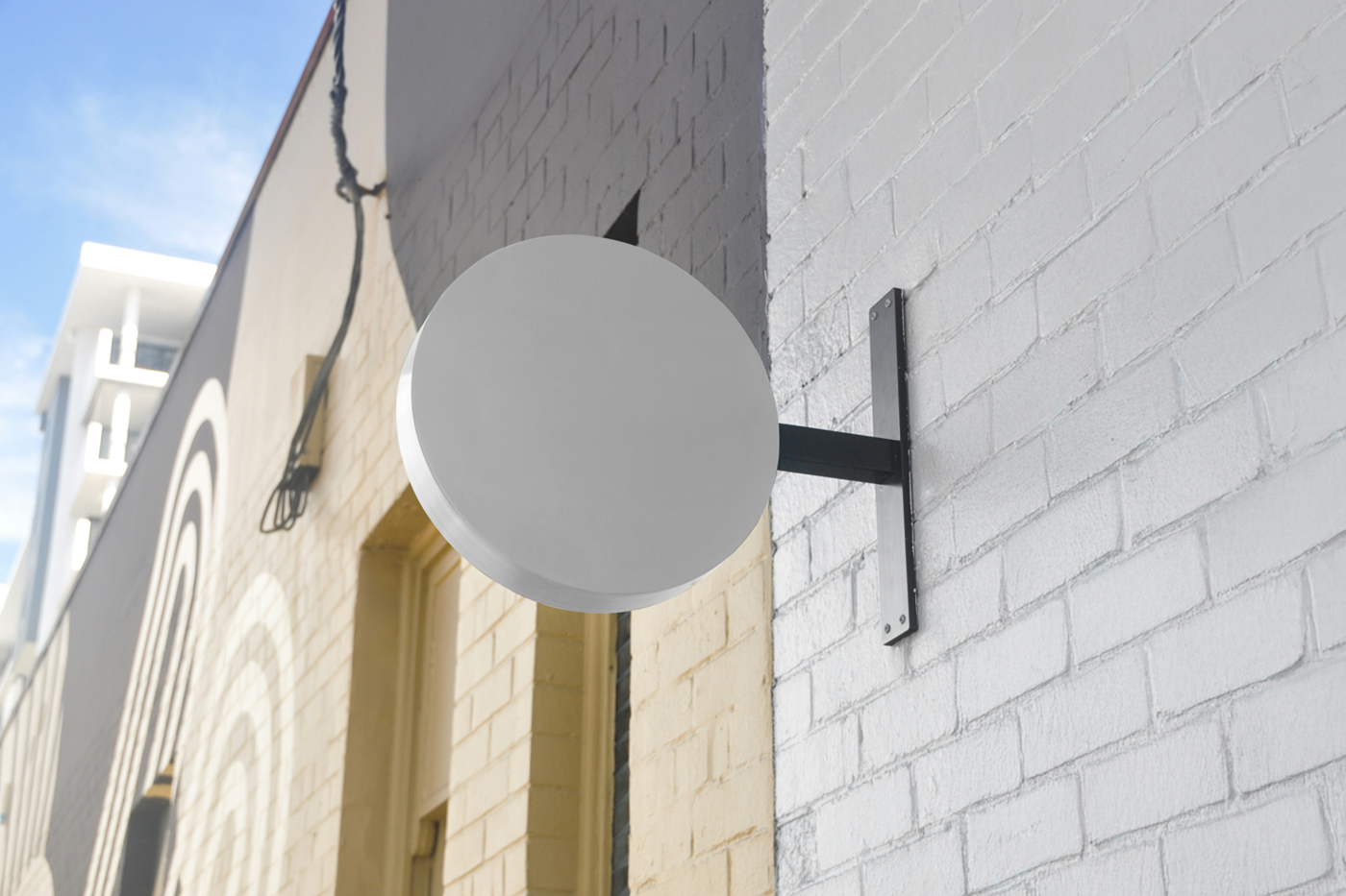 Front view, a White Circle Signage Attached to Wall Mockup against the brick building.