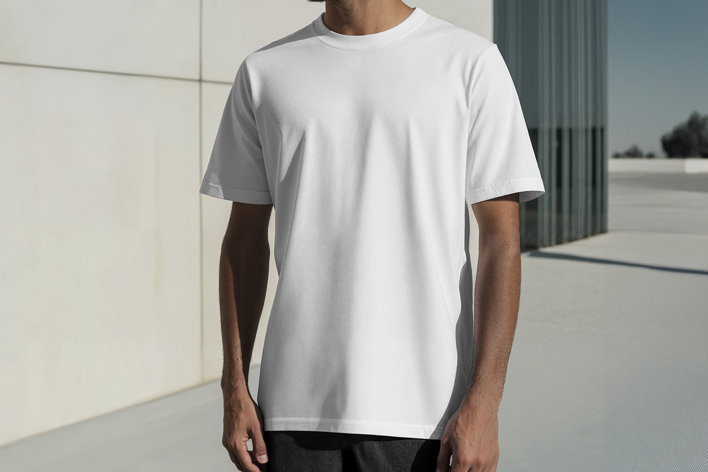 Standing men wearing a White T-Shirt Mockup with a blue and black logo in front of the white wall.