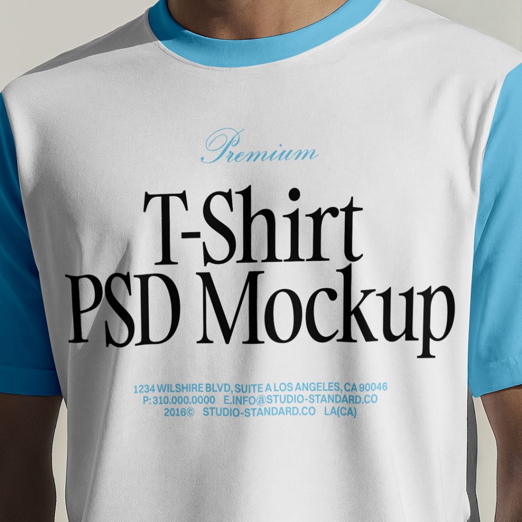 Standing men wearing T-Shirt Mockup with a blue and black logo in front of the white wall.