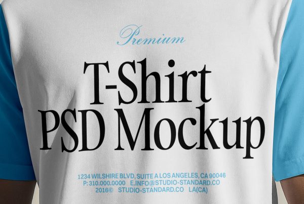 Standing men wearing T-Shirt Mockup with a blue and black logo in front of the white wall.