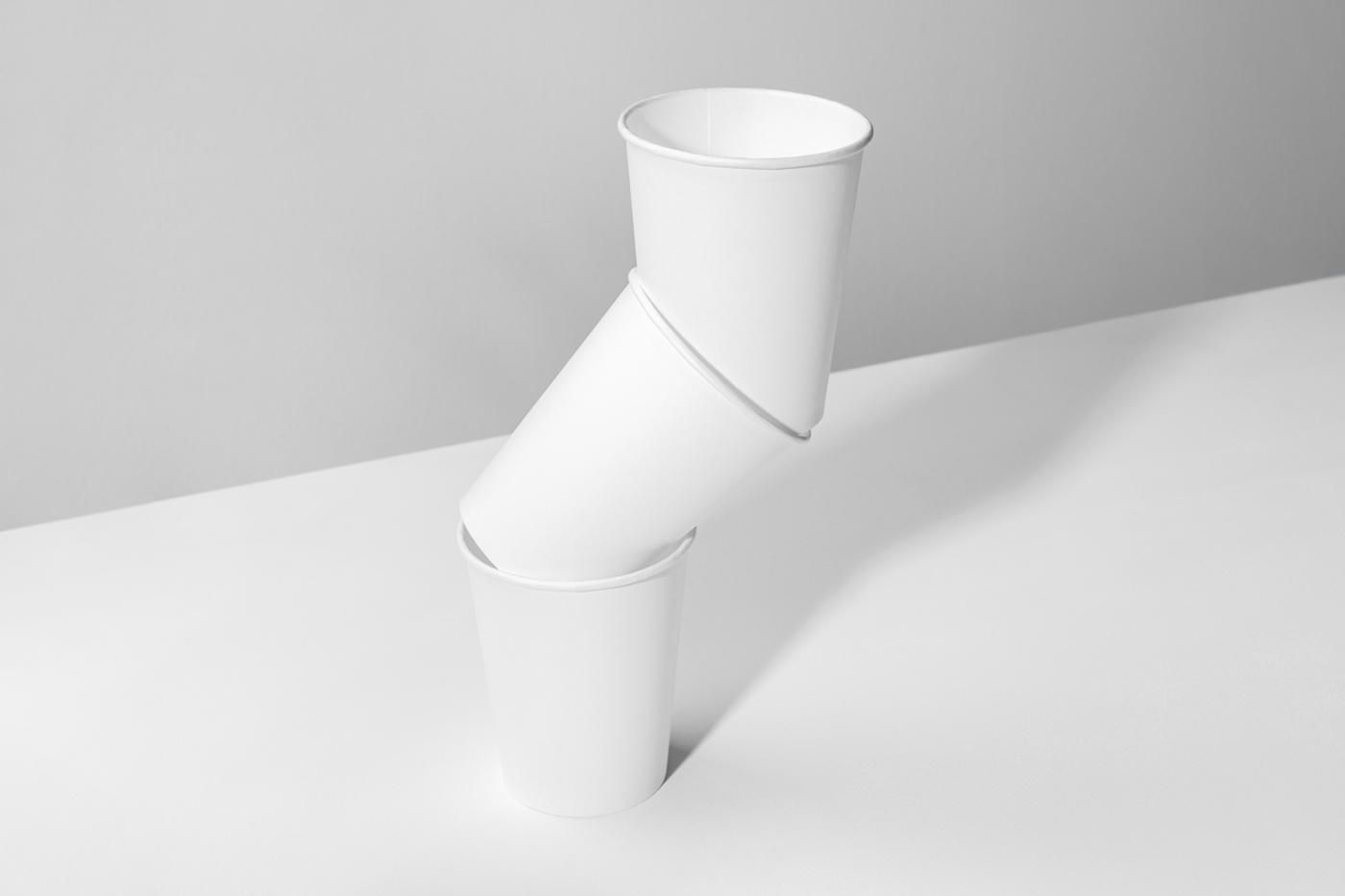 Front view, a White Three Coffee Cup Mockups standing on the bright gray background.