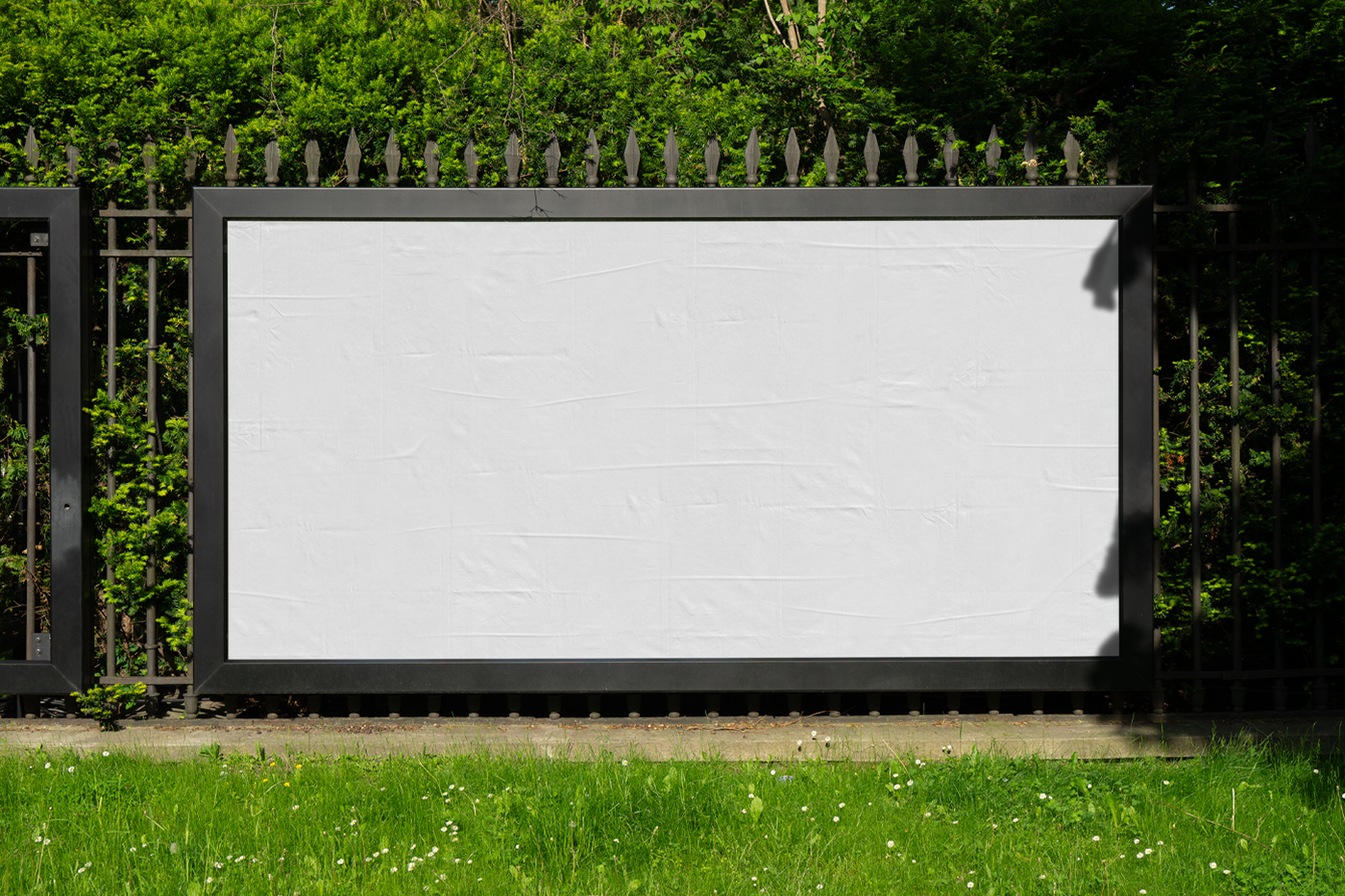 Front view, a White Wide Outdoor Billboard Mockup attached to the metal fence against the city garden.