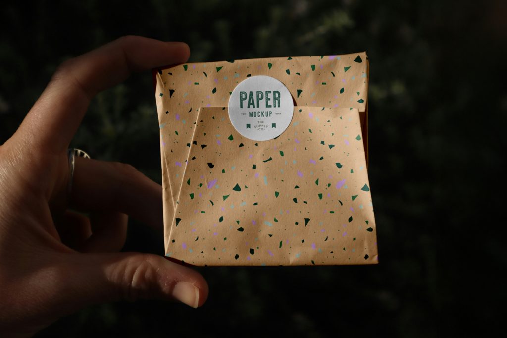 Front view, Wrapping Paper Package Mockup with circle sticker and terrazzo design patter against black background.