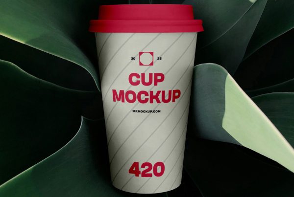 View from above, coffee cup mockup with strong, simple typography design surrounded by plants.
