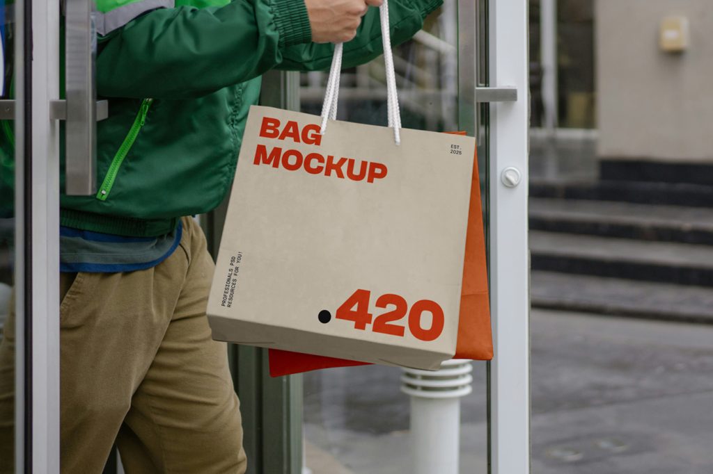 Front view, two delivery bag mockups with simple typography designs in beige and orange colors holding by men in green jacket and beige pants.