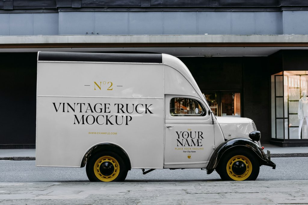 Front view, a white mini truck mockup with serif typography design in black and gold color parked against the building.