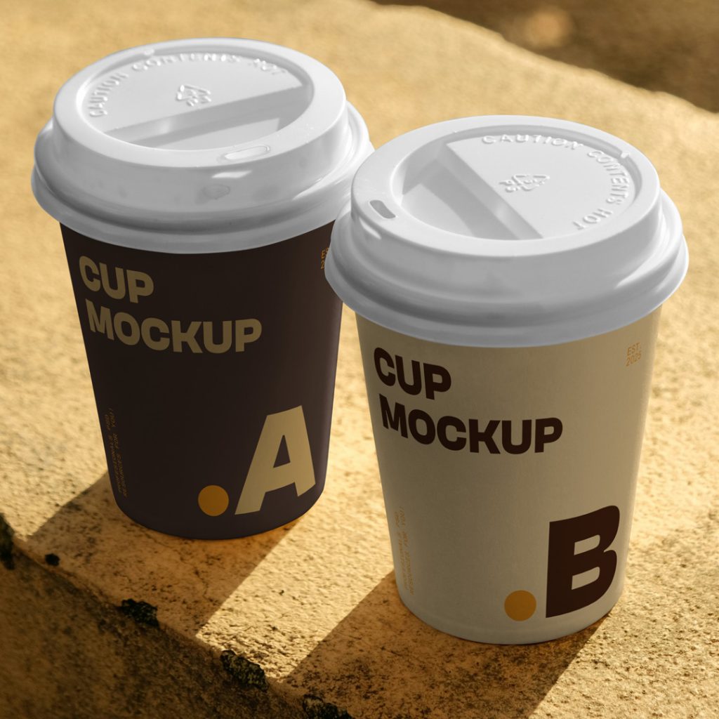 View from above, two paper cup mockups with simple typography design in brown and beige colors standing on a concrete wall.