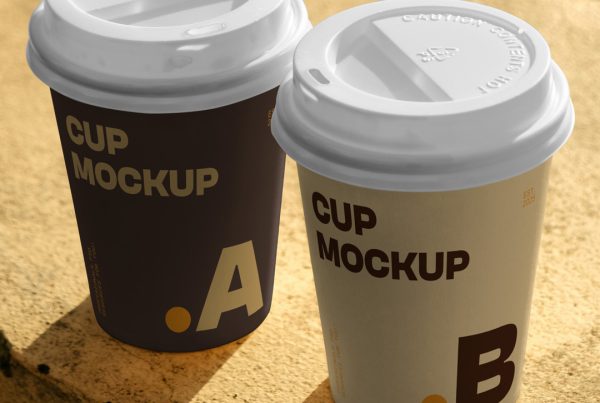 View from above, two paper cup mockups with simple typography design in brown and beige colors standing on a concrete wall.