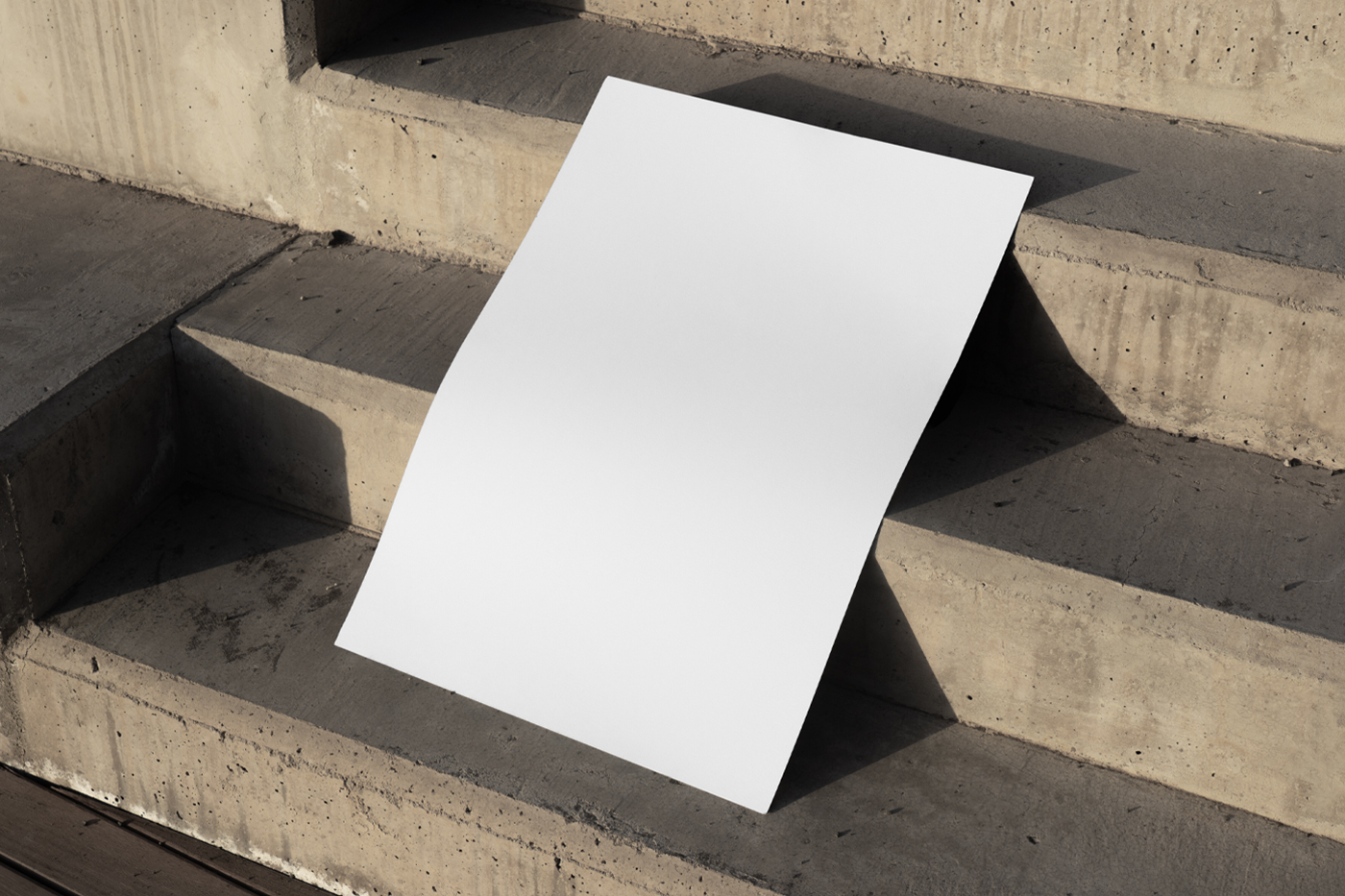 View from above, a white poster mockup lying on the concrete stairs.