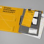 Front view, stationery mockups. Open yellow binder mockup with a white A4 card mockup, white business card mockups, yellow leaflet mockup, and black square card mockup lying on it, strong geometric typography design in yellow, black, and white colors. Everything is lying on a bright gray background.