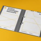 Front view, stationery mockups. Open dark gray binder mockup, two white A4 card mockups with black typography and yellow stroke lines. Everything is lying on a yellow background.