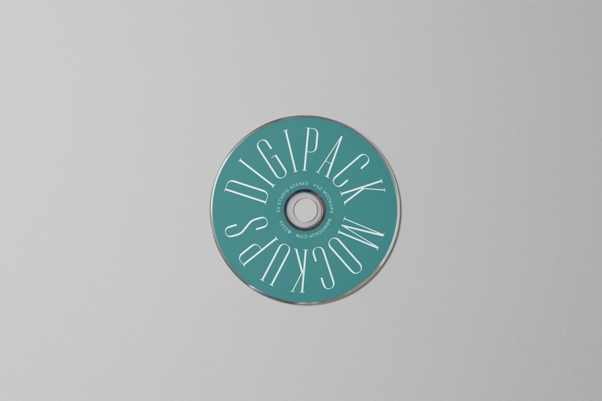 Viewed from above, CD Digipack Mockups presents a green disc with nice white serif typography lying on the gray background.
