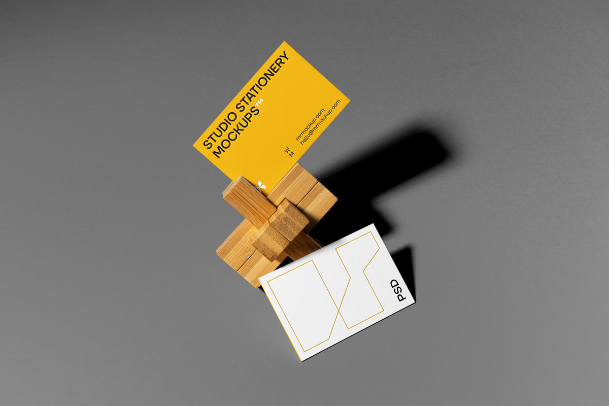 Front view, stationery mockups of two business cards with a wooden toy lying on the gray background.