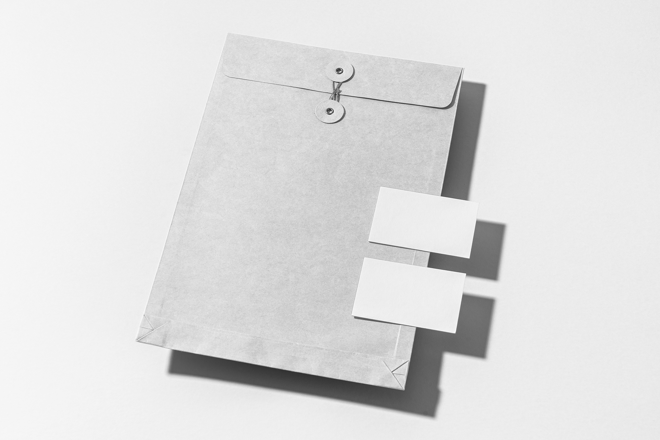 Front view, stationery mockups. Close white envelope mockup and two white business card mockups lying on it. Everything is lying on a white background.