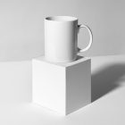 Front view, stationery mockups of a white square box mockup and the white cup mockup. Everything is lying on a white background.