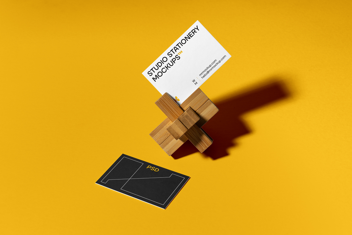 Front view, stationery mockups of two business cards, mockup with wooden toy lying on the yellow background.