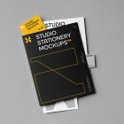 Front view, stationery mockups. A black folder mockup with a protruding yellow leaflet mockup, a white A4 mockup, and a grey business card mockup. Everything is lying on a grey background.