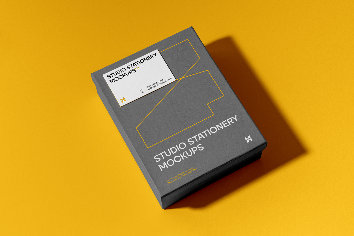 View from above, grey box mockup with a visible white business card mockup lying on it, strong geometric typography design in yellow, white, and black colors. Everything is lying on a yellow background.