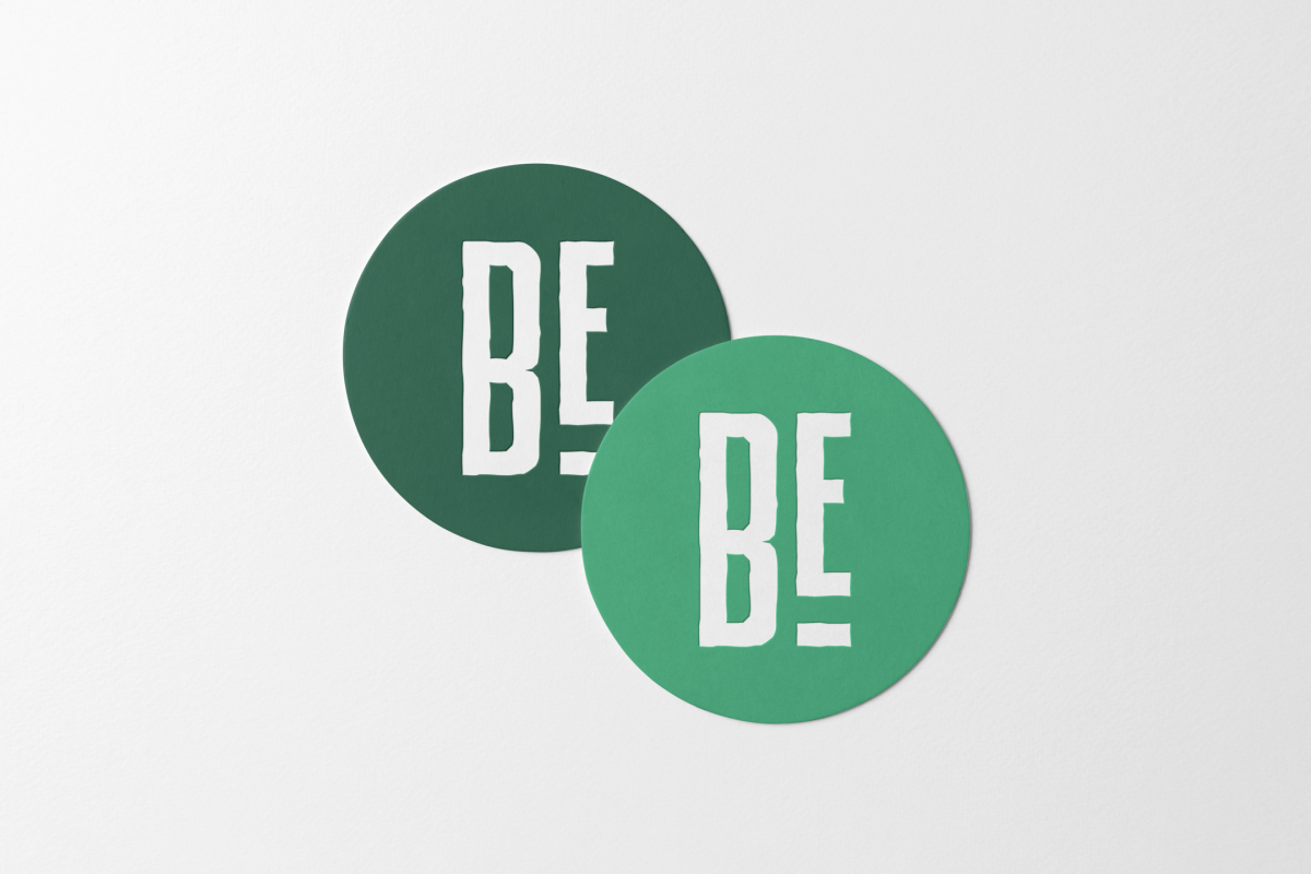 Viewed from above, two circle beer pad mockups in two green shades and a white condensed logo lying on the white background.