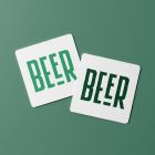 Viewed from above, two beer pad mockups in white and two in green condense the logo lying on the green background.