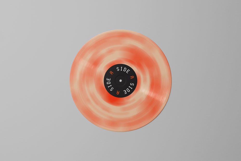 Viewed from above, Vinyl Mockups presents a vinyl disc with pressed graphics in two colors lying on the gray background.