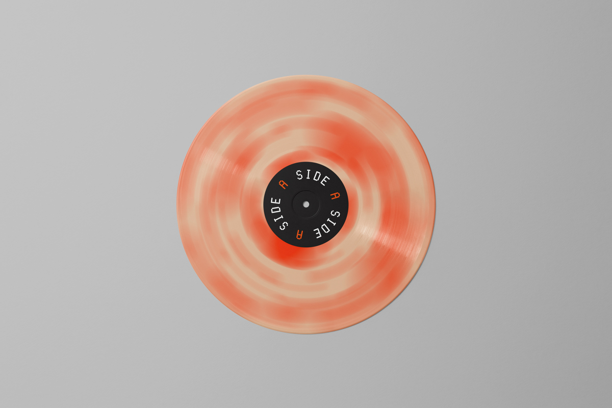 Viewed from above, Vinyl Mockups presents a vinyl disc with pressed graphics in two colors lying on the gray background.