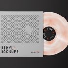 Viewed from above, Vinyl Mockups presents a square music album cover in a gray color with a metal fence graphic and an ejected vinyl disc with pressed graphics in two colors lying on a black background.