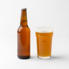 Front view of a standing beer bottle mockup transparent beer glass mockup standing on the white floor.