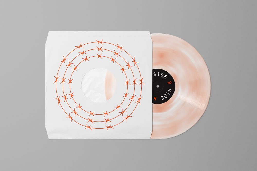 Viewed from above, Vinyl Mockups presents a vinyl disc package in a white color with a metal fence graphic and an ejected vinyl disc with pressed graphics in two colors lying on a gray background.