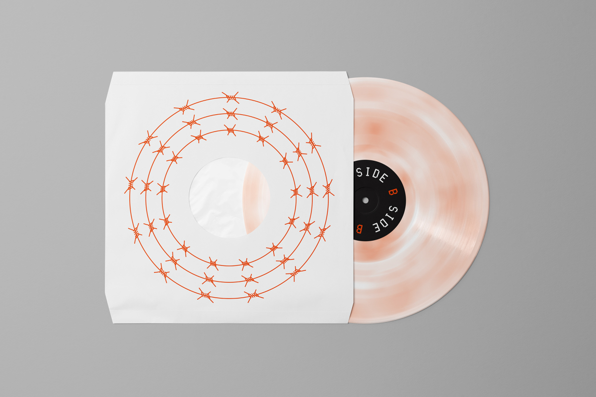 Viewed from above, Vinyl Mockups presents a vinyl disc package in a white color with a metal fence graphic and an ejected vinyl disc with pressed graphics in two colors lying on a gray background.