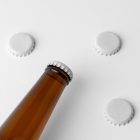 View from above, beer bottle mockup with three white beer crown cap mockups lying on the white background.