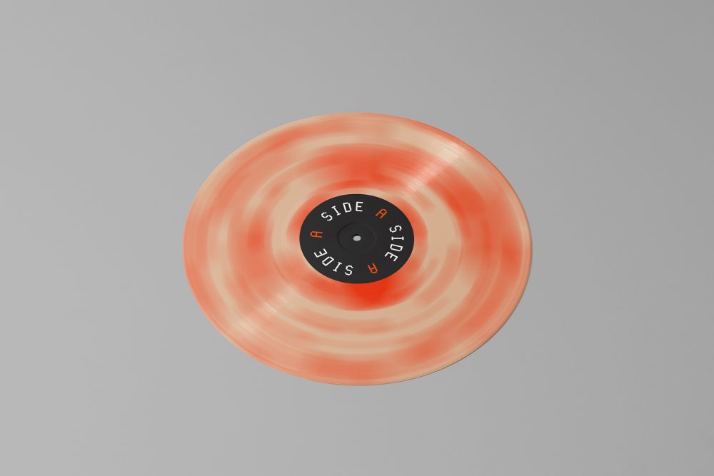 Viewed from above, Vinyl Mockups presents a vinyl disc with pressed graphics in two colors lying on the gray background.