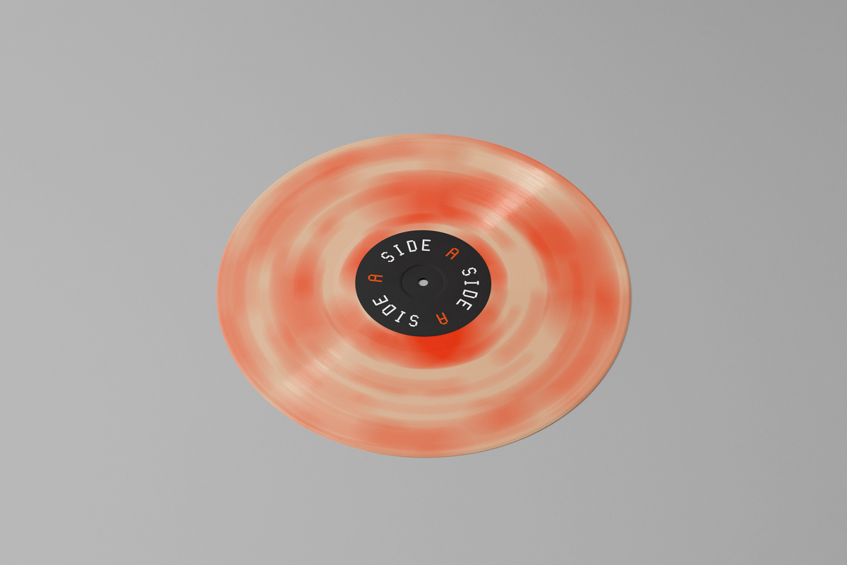 Viewed from above, Vinyl Mockups presents a vinyl disc with pressed graphics in two colors lying on the gray background.