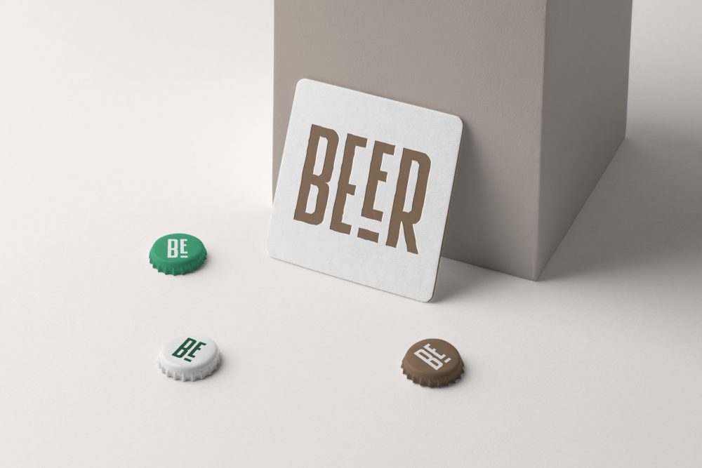 Front view, a white beer pad mockup leans on a beige box, and three beer crown cups lying on the white background.