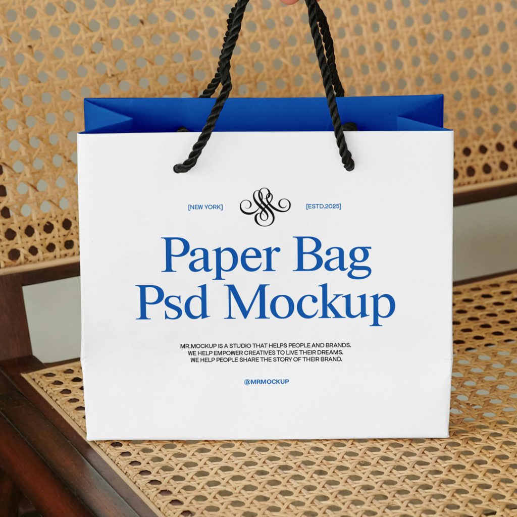 Front view, paper bag mockup with black and blue typography design standing on the vintage chair.