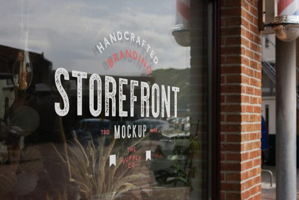 Front view, at an angle of 45 degrees, clean glass restaurant storefront mockup with red graphics elements and white delicate serif typography.