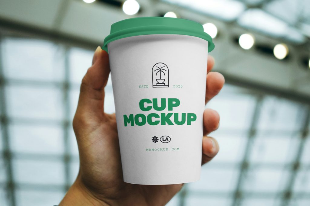 Front view of a bright-green coffee cup mockup with a strong typography design held by a man's hand.